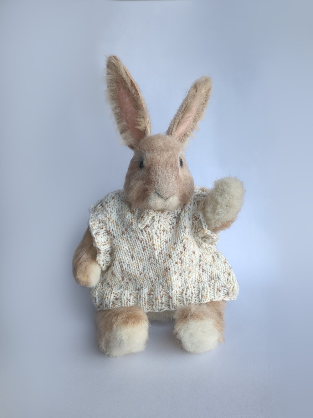 A handcrafted doll of Peetah the rabbit, wearing a hand-knitted cream-colored sweater
